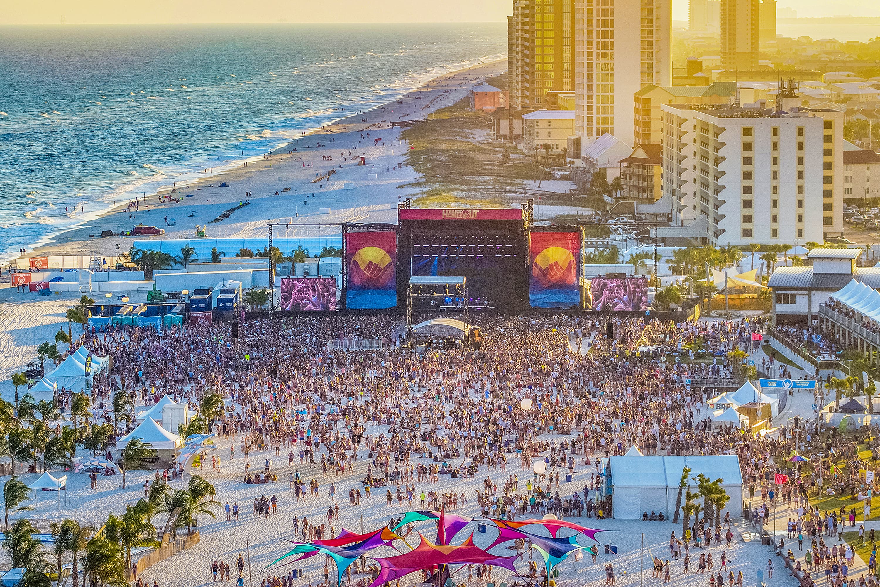 The concert-goers enjoy dancing on the sand at this outdoor beach festival.